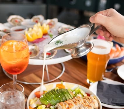 A person pouring wine over a plate of food at Smyth Taverna; Enhancing the flavors with a splash of wine over a delicious plate of food.