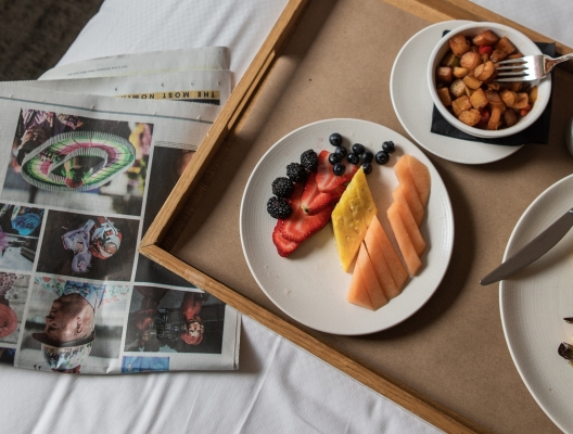 A woman in a robe sitting on a bed with a tray of food.