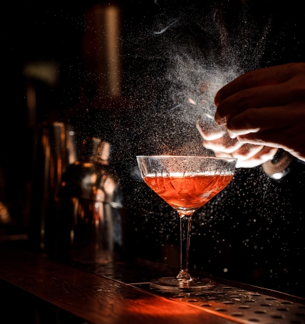 Bartender's hands sprinkling the juice into the cocktail glass
