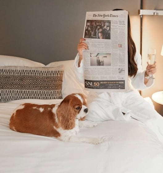 Woman enjoying her day in bed with her doh at Smyth Tribeca Hotel.