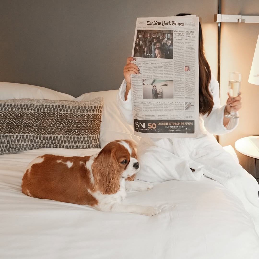 Woman enjoying her day in bed with her doh at Smyth Tribeca Hotel.