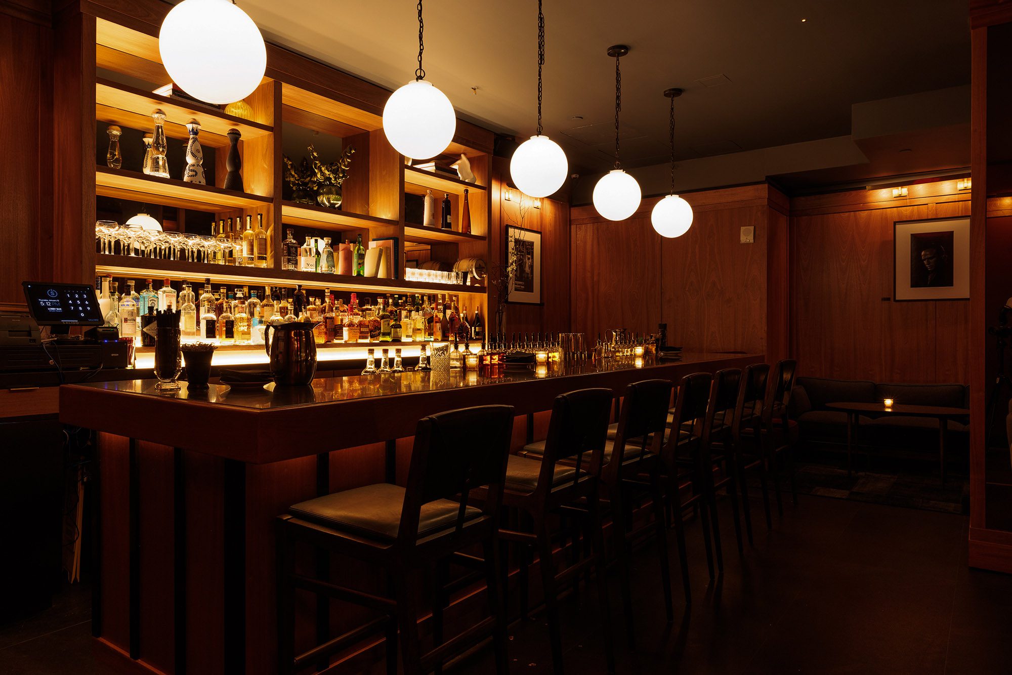 a dimly lit bar with a long counter and stools