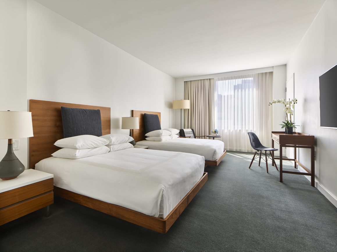 A hotel room with two double beds, a desk, and a window.