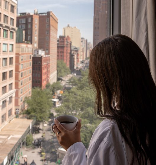 Woman enjoying coffee at her Tribeca hotel window