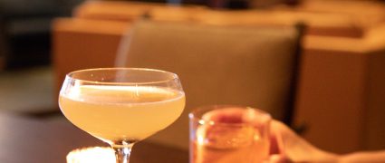 A woman enjoying a cocktail while seated at a table.