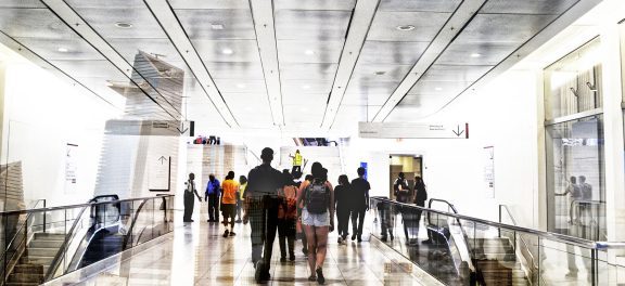 Shot of unrecognizable people walking on subway station superimposed over a cityscape. The city is NYC, Hudson Yards.