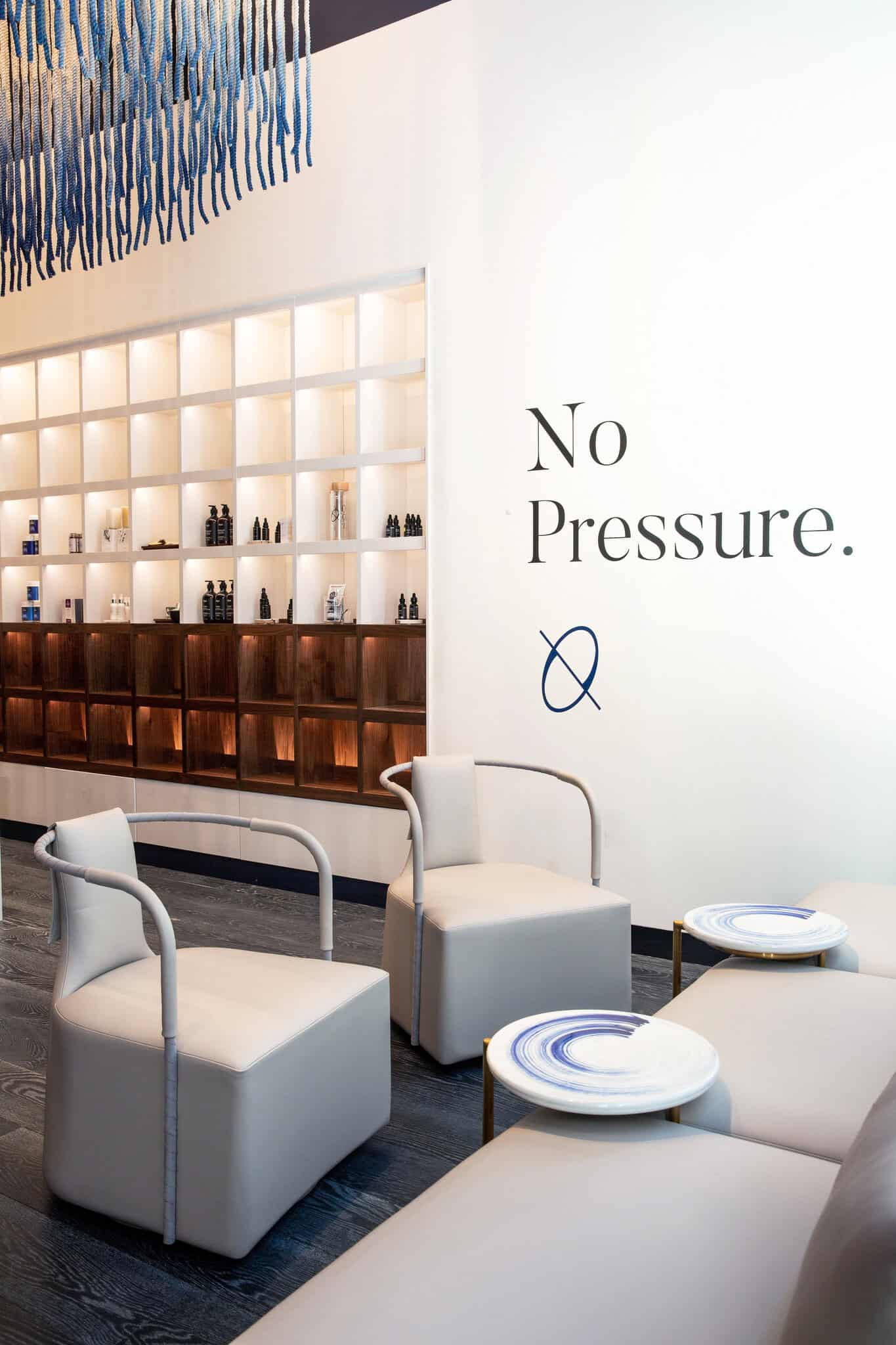 a spa lobby with a shelving unit full of products, two chairs, and a table